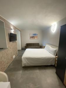 a bedroom with a white bed and a couch at airport apartments camera relax in San Maurizio Canavese