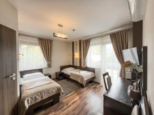 a hotel room with two beds and a desk at Hotel Mieszko in Rzeszów