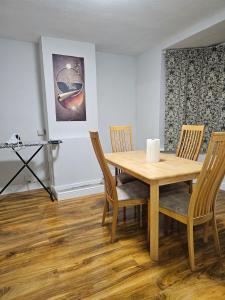 a dining room with a wooden table and chairs at Three bedroom house with a park in Dagenham