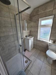 a bathroom with a shower and a toilet and a sink at Three bedroom house with a park in Dagenham
