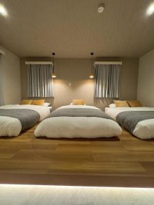 a bedroom with three beds in it with windows at Make Your Hotel幡ヶ谷 in Tokyo