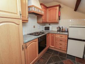 a kitchen with wooden cabinets and a stove top oven at Freesia Cottage in Wooler