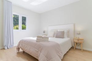 una camera da letto bianca con un letto bianco con asciugamani sopra di Casa da Hortência do Faial a Faial