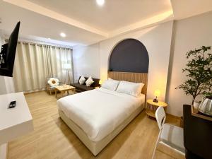 a bedroom with a white bed and a living room at Brown House Cha am in Cha Am