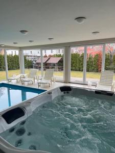 a hot tub in a house with chairs and windows at AH-Corso Wellness Panorama Apartman in Siófok