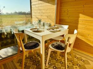 une table blanche et des chaises dans une pièce avec une fenêtre dans l'établissement Hochwertiges Tiny House 'Elbhütte' mit Wiesenblick 101, à Bleckede