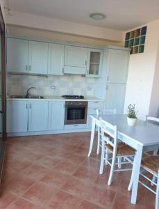a kitchen with white cabinets and a table and chairs at La Pelosa House 1 in Stintino