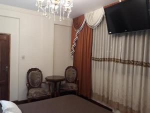 a bedroom with two chairs and a table and a television at Hostal Terrabella SRL in La Paz