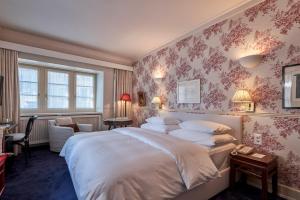 um quarto com uma cama grande e papel de parede rosa em Hotel Kindli em Zurique