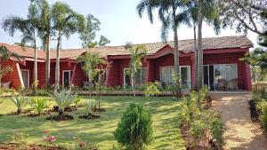 a red house with palm trees in a yard at Whispering Woods Resort in Lonavala