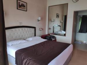 a bedroom with a large bed and a mirror at Whispering Woods Resort in Lonavala +29 photos