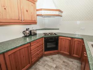 a kitchen with wooden cabinets and a stove at Lavender Cottage in Wooler