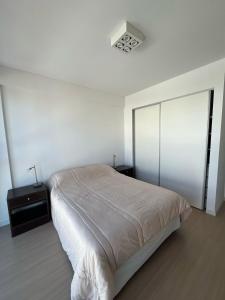 a white bedroom with a bed and two night stands at Gorriti Apartment in Lomas de Zamora