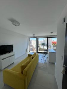 a living room with a yellow couch and some windows at Gorriti Apartment in Lomas de Zamora