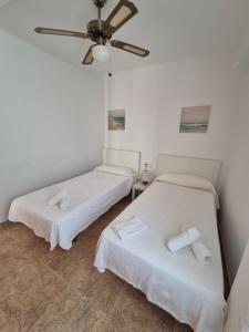 two beds in a room with a ceiling fan at 3ºB Escobar in Nerja