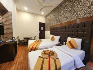 a hotel room with two beds and a table at Hotel Raunak in Kolkata