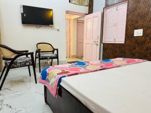 a bed in a room with two chairs and a tv at Kamaree-7BHK in Varanasi