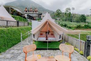 a teepee tent with two chairs and a table at Glamping Telaga Menjer By Travelink in Kejajar