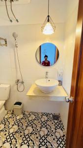 a man taking a picture of a bathroom with a sink at Vang's Homestay - Huế in Ấp Long Hồ Hạ