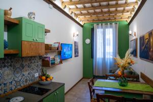 a kitchen and dining room with green cabinets and a table at Antichi Sapori Appartamenti in Trapani