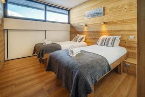 two beds in a room with a window at Chalet Arktic - Catered Chalet - Sleeps 14 in Tignes