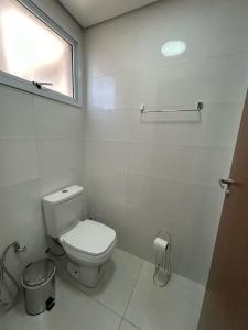 a white bathroom with a toilet and a window at Flat novíssimo,somente famílias ,e completo centro Ribeirão pr in Ribeirão Preto