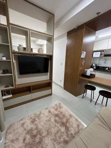 a living room with a large television and a kitchen at Flat novíssimo,somente famílias ,e completo centro Ribeirão pr in Ribeirão Preto