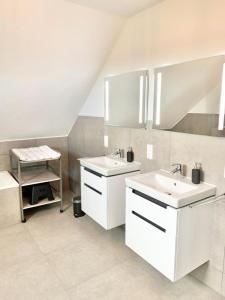 a white bathroom with two sinks and a bench at Traumhaus am See und Küste für die ganze Familie in Wangerland