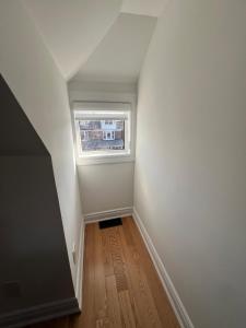 an empty room with a window and a wooden floor at Mark & Ana Guest House in Toronto