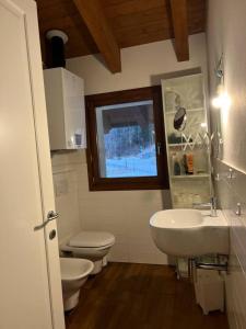 a bathroom with a sink and a toilet and a window at Inserrata Abetone in Tuscany in Abetone