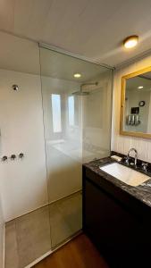 Un baño con ducha, lavabo y espejo. en Cauquenes Suites, en Río Gallegos