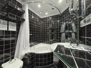 a black tiled bathroom with a tub and a toilet at Hotel Plata in Ibi