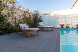 two chairs sitting on a deck next to a swimming pool at CASA DAS PORTAS VELHAS by Stay in Alentejo in Vila Nova de Milfontes