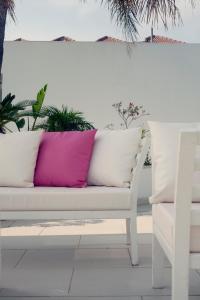 un sofá blanco con una almohada rosa junto a una silla en L'eros Hotel, en Ayia Napa