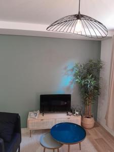 a living room with a blue table and a tv at Le coucou, studio tout équipé proche gare in Saint-Brieuc