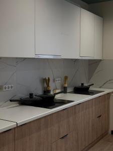 a kitchen with white cabinets and black pans on the counter at Estet Boutique Hotel in Astana