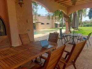a laptop sitting on a wooden table on a patio at Villa Michel Lucas in Marrakesh