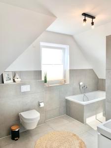 a white bathroom with a toilet and a bath tub at Landhaus an der Nordsee mit Garten und Sauna! in Butjadingen