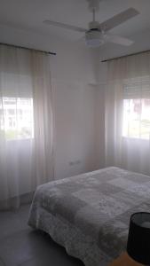 a white bedroom with a bed and two windows at Frente al mar in Pinamar