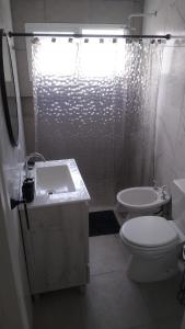 a bathroom with a toilet and a sink and a shower at Frente al mar in Pinamar +11 photos