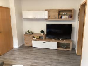 ein Wohnzimmer mit einem Flachbild-TV auf einem hölzernen Entertainment-Center in der Unterkunft Landhaus Saterland Ferienwohnung in Sedelsberg