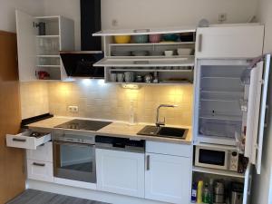 eine Küche mit weißen Schränken und einer Spüle in der Unterkunft Landhaus Saterland Ferienwohnung in Sedelsberg + 24 Fotos