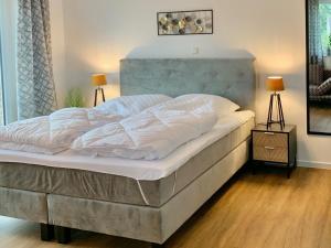 a large bed with white sheets and pillows on it at Neues Ferienhaus für Familien mit Garten und Sauna in Butjadingen