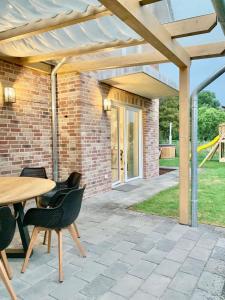 a patio with a table and chairs under a wooden pergola at Neues Ferienhaus für Familien mit Garten und Sauna in Butjadingen