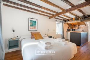 1 dormitorio con 1 cama blanca grande y techos de madera en MyHouseSpain - Apartamentos Cudillero, en Cudillero