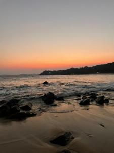 a sunset on the beach with rocks in the sand at Star Beach Villa in Tangalle