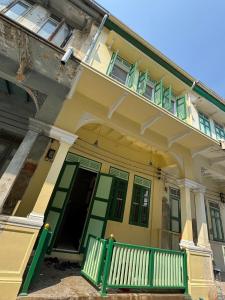 ein gelbes Haus mit grünen Rollläden und einem Balkon in der Unterkunft Luan Heritage Surawong in Bangkok