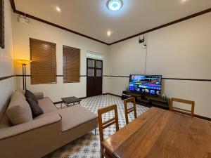 ein Wohnzimmer mit einer Couch, einem Tisch und einem Fernseher in der Unterkunft Luan Heritage Surawong in Bangkok