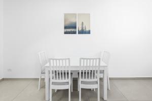 a white dining room table with four chairs and a picture at Luxury Penthouse With Sea View #65 By Hashdera Eilat in Eilat