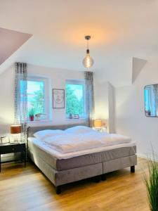 ブットヤーディンゲンにあるTraumhaus mit Platz für 20 Personen an der Nordseeの大きなベッドと2つの窓がある寝室
